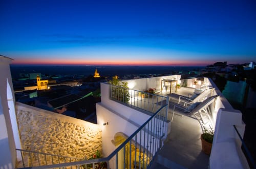Terraza en la azotea al atardecer en La Vista Medina Stays de Medina Sidonia con espacios iluminados y vistas del horizonte al atardecer