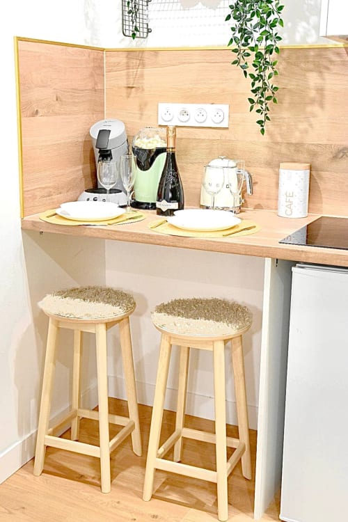 Compact kitchenette with wooden counter, bar stools, and appliances at Wellkhome Bordeaux apartment
