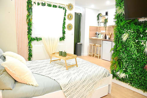 Modern Bordeaux apartment with lush green wall plants, wooden bed, kitchenette, and natural lighting at Wellkhome
