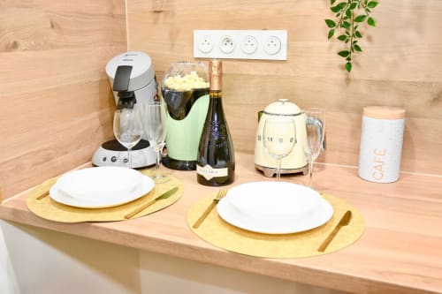 Elegant dining setup for two at Wellkhome Bordeaux with champagne, coffee maker, and place settings on wooden table