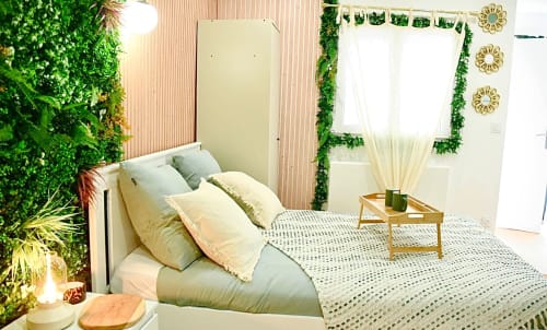 Modern bedroom at Wellkhome Bordeaux with green plant walls, cream bedding, wooden nightstand, and natural lighting