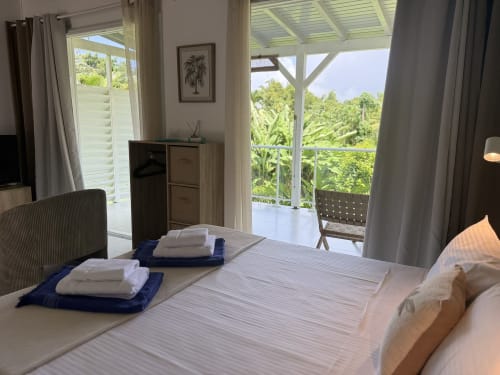 Modern bedroom at Domaine de la Glacière in Petit Bourg with balcony view of lush tropical gardens