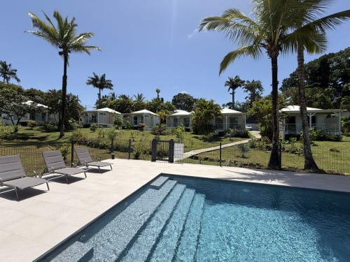 Piscine du Domaine de la Glacière avec transats, palmiers et Bungalows Héliconia à Petit-Bourg, Guadeloupe