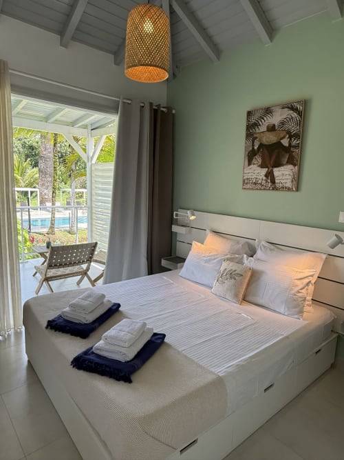 Chambre Bungalow Héliconia à la Domaine de la Glacière, Petit Bourg, vue piscine, murs menthe et mobilier moderne