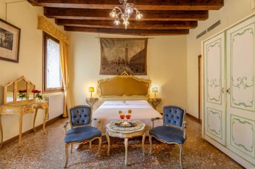 Chambre vénitienne somptueuse au Palazzo San Firmino avec lit doré, fauteuils bleus, vue sur le canal et carrelage en terre cuite