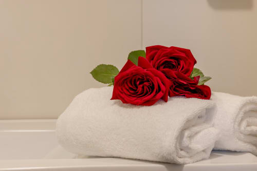 Roses rouges sur serviettes blanches enroulées dans une chambre d'hôtel de luxe à Venise avec équipements