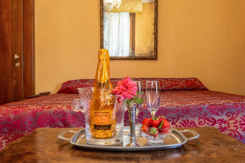Champagne, fleur rose et fraises fraîches sur la table de la Suite King de l'hôtel Venezia avec lit et miroir