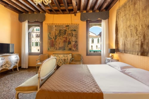 Suite Royale luxueuse au Palazzo San Firmino à Venise avec murs ocre chauds, plafond à poutres en bois et vue sur le Grand