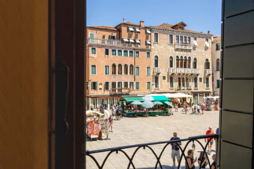 Vue de la place de Venise depuis le balcon de la suite King au Palazzo San Firmino, avec bâtiments historiques et étals du marché