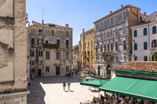 Place du Grand Canal à Venise avec palais historiques, auvents verts et vue sur le waterfront depuis le Palazzo San Firmino