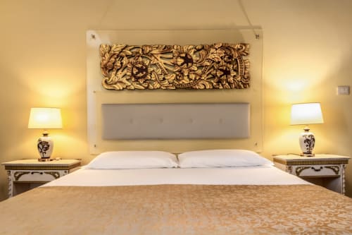 Chambre élégante au Palazzo San Firmino Venise avec tête de lit capitonnée, boiseries sculptées ornées, lampes jumelées et marbre