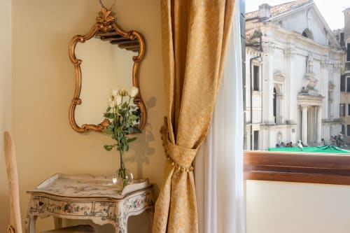 Élégante Junior Suite du Palazzo San Firmino à Venise avec miroir orné, fleurs fraîches et vue sur le canal historique