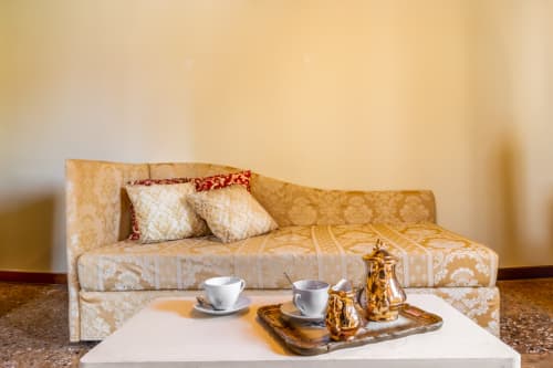 Élégant canapé beige avec coussins décératifs et service à thé doré dans la Junior Suite du Palazzo San Firmino, Venise