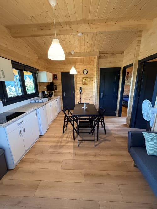 Interno di lodge moderno con soffitti in legno, tavolo da pranzo, cucina bianca e porte nere alle Cabanes et lodges du Belvédère