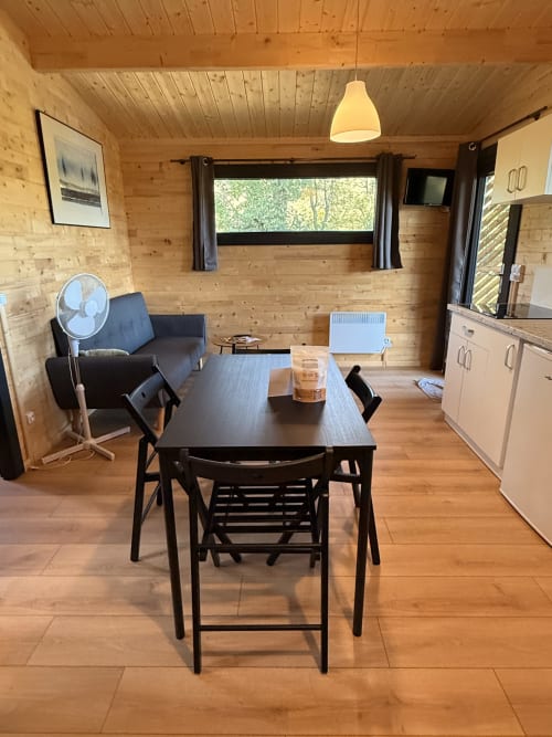Interno moderno del lodge Cabanes du Belvédère con tavolo da pranzo, zona salotto e cucina in spazio rivestito di legno