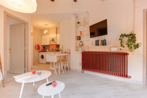 Villa nórdica moderna Buhardilla en Salamanca con salón, cocina, radiador rojo, mesas blancas, estantería y televisor