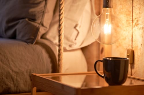 Acogedor dormitorio nórdico en MoneoHeritage Salamanca con lámpara colgante, taza negra y muebles de madera rústica