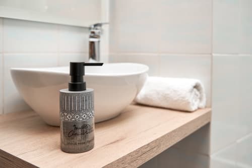 Lavabo moderno con cerámica blanca y dispensador de jabón decorativo sobre mesada de madera en villa hotel de Salamanca