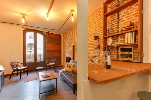 Sala de estar tipo loft industrial en hotel Salamanca con ladrillo visto, estanterías de madera, muebles modernos y vistas a la ciudad