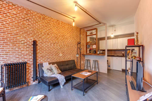 Estudio loft industrial con paredes de ladrillo visto, sofá negro, cocina y vistas emblemáticas en hotel Salamanca