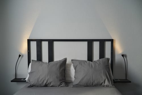 Dormitorio loft industrial moderno en el hotel MoneoHeritage de Salamanca con almohadas grises, cabecero negro e iluminación ambiental lateral