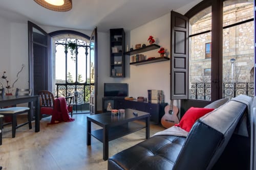 Elegante sala de estar en hotel de Salamanca con muebles negros, guitarra, vistas de balcón al monumento y comodidades modernas