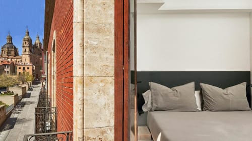Habitación Mirador Clásico en MoneoHeritage en Salamanca con cama y vistas a la emblemática catedral histórica desde el balcón