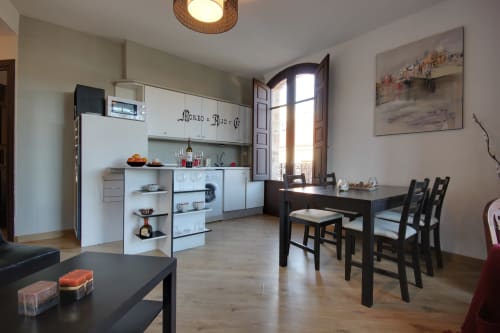 Cocina y comedor moderno en villa de Salamanca con muebles blancos, mesa de comedor negra y vistas al monumento a través de arcos