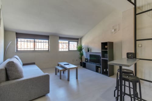 Sala de estar minimalista moderna en villa de Salamanca con sofá, mueble TV, mesa de comedor y amplios ventanales