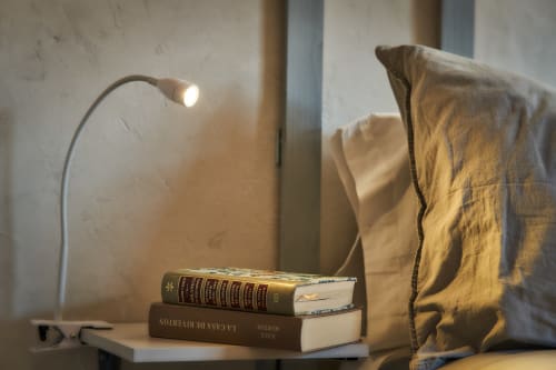 Acogedor rincón de lectura en MoneoHeritage Salamanca con libros apilados, lámpara de escritorio y lino ocre en habitación de villa