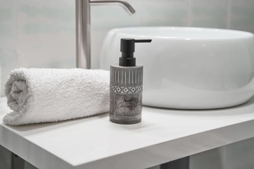 Lavamanos moderno del hotel MoneoHeritage con toalla blanca enrollada, dispensador de jabón decorativo y elegante grifo