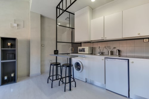 Cocina minimalista moderna con muebles blancos, lavadora y barra de bar en Alojamiento Turístico MoneoHeritage