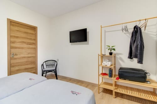 Habitación moderna en MoneoHeritage en Salamanca con camas gemelas, muebles de madera, TV montada en pared y almacenamiento organizado
