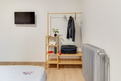 Habitación del hotel MoneoHeritage en Salamanca con muebles de madera, TV, calefacción por radiador y almacenamiento organizado