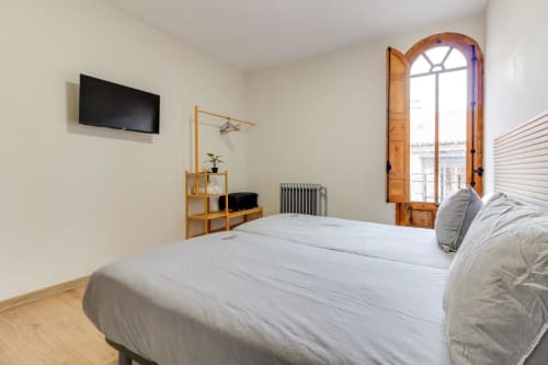 Luminosa habitación en hotel de Salamanca con cama doble, TV de pantalla plana y puertas de madera que abren a balcón