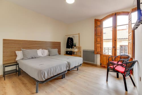 Amplio dormitorio con cama de madera, sillas rojas y puertas a la terraza en el hotel MoneoHeritage, Salamanca