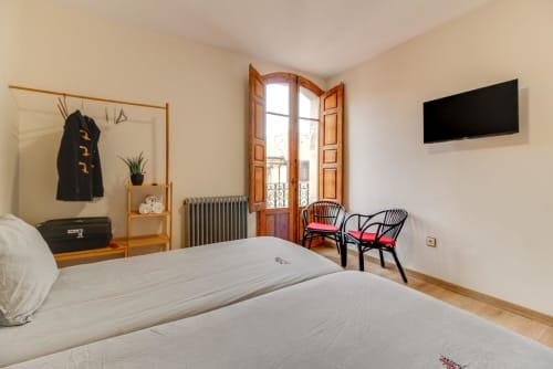 Habitación luminosa en Salamanca con camas gemelas, armario de madera, puertas de balcón y comodidades modernas