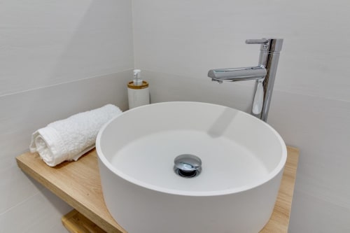 Lavabo circular blanco moderno con grifo cromado en el apartamento Estudio San Pablo del hotel MoneoHeritage, Salamanca