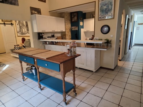 Offene Küche und Essbereich im Cottage Le Manoir Lacustre mit blauem Arbeitstisch und weißen Schränken