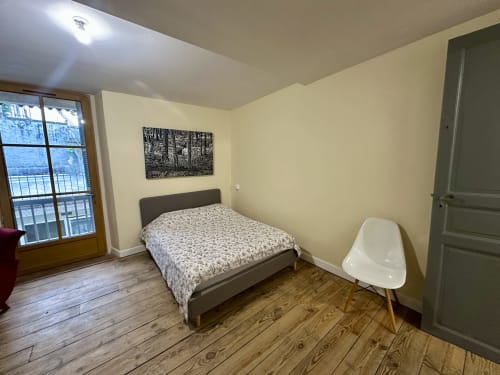 Nowoczesna sypialnia w Ombre de la Tour, Lourdes z łóżkiem, dostępem do balkonu, drewnianymi podłogami i widokiem na ogród