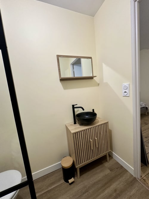 Nowoczesna umywalka łazienkowa z czarną muszlą ceramiczną i drewnianą szafką w apartamencie Ombre de la Tour, Lourdes
