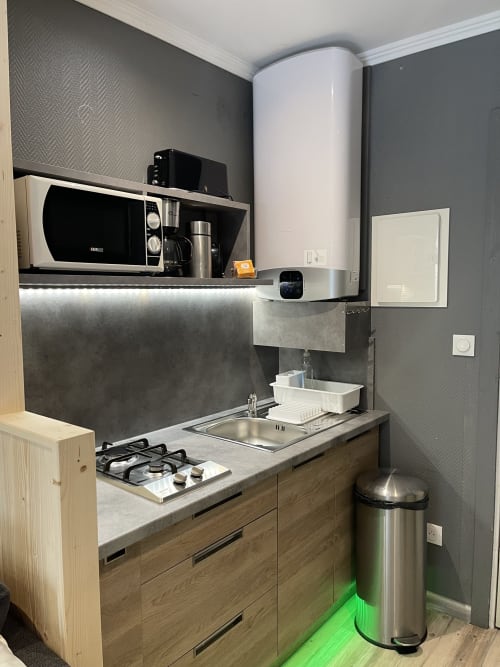 Kitchenette moderne à La Montagnette B&B à Moutiers avec cuisinière à gaz, évier, micro-ondes et poubelle inox