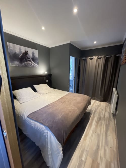 Chambre moderne à la Guesthouse La Montagnette à Moutiers avec murs sombres, lit queen-size, TV écran plat et accès vue sur la ville