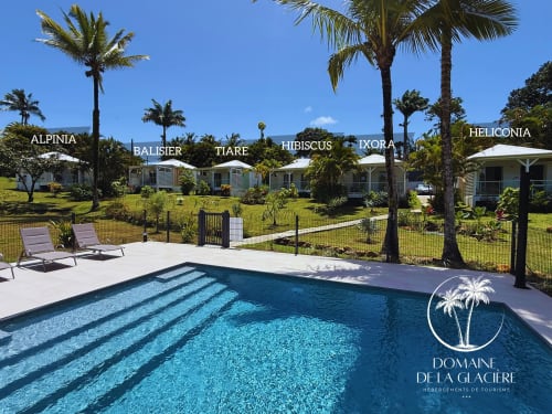 Piscine du Domaine de la Glacière avec bungalows à Petit-Bourg, Guadeloupe - eau turquoise, palmiers, resort tropical ensoleillé