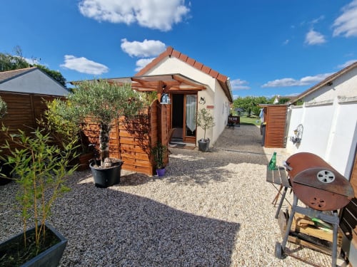 Cour extérieure du studio Le Loup à Lamotte-Beuvron avec terrasse privée, barbecue, bambous et olivier en pot, offrant un espace détente convivial au cœur de la Sologne.