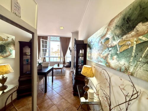 Elegante sala de estar con vistas al mar, muebles de madera oscura, lámparas amarillas y arte botánico en Baiona