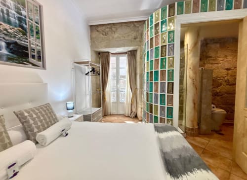 Habitación boutique Solpor en Baiona con vistas al mar, cama blanca, baño privado y detalles de azulejos coloridos
