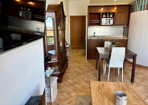 Cocina y comedor moderno en apartamento Solpor, Baiona con muebles de madera, ventanal con vistas al mar y todas las comodidades