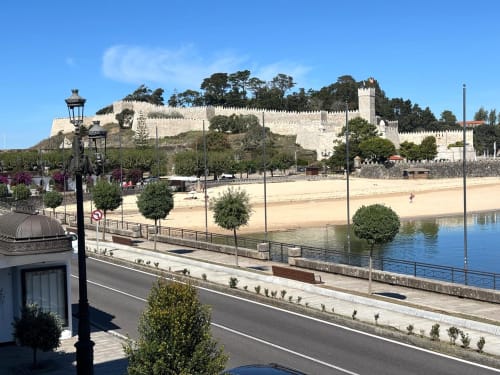 Castillo medieval con vistas a playa de arena y paseo marítimo en Baiona, España