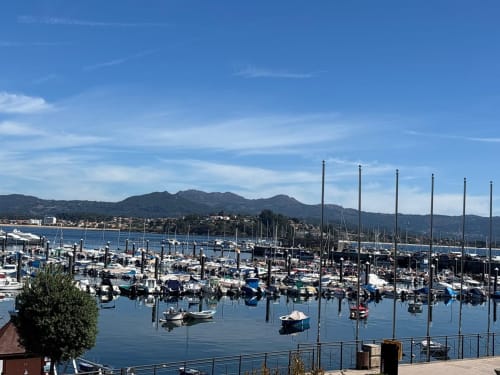 Bahía de Baiona con veleros, montañas y vistas del pueblo costero desde el balcón del apartamento Solpor